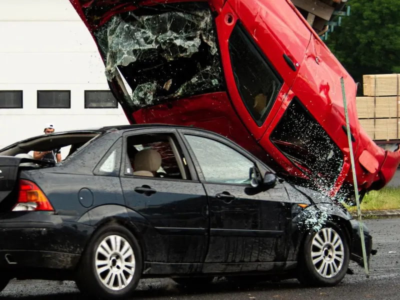 A red car crashing onto a black sedan